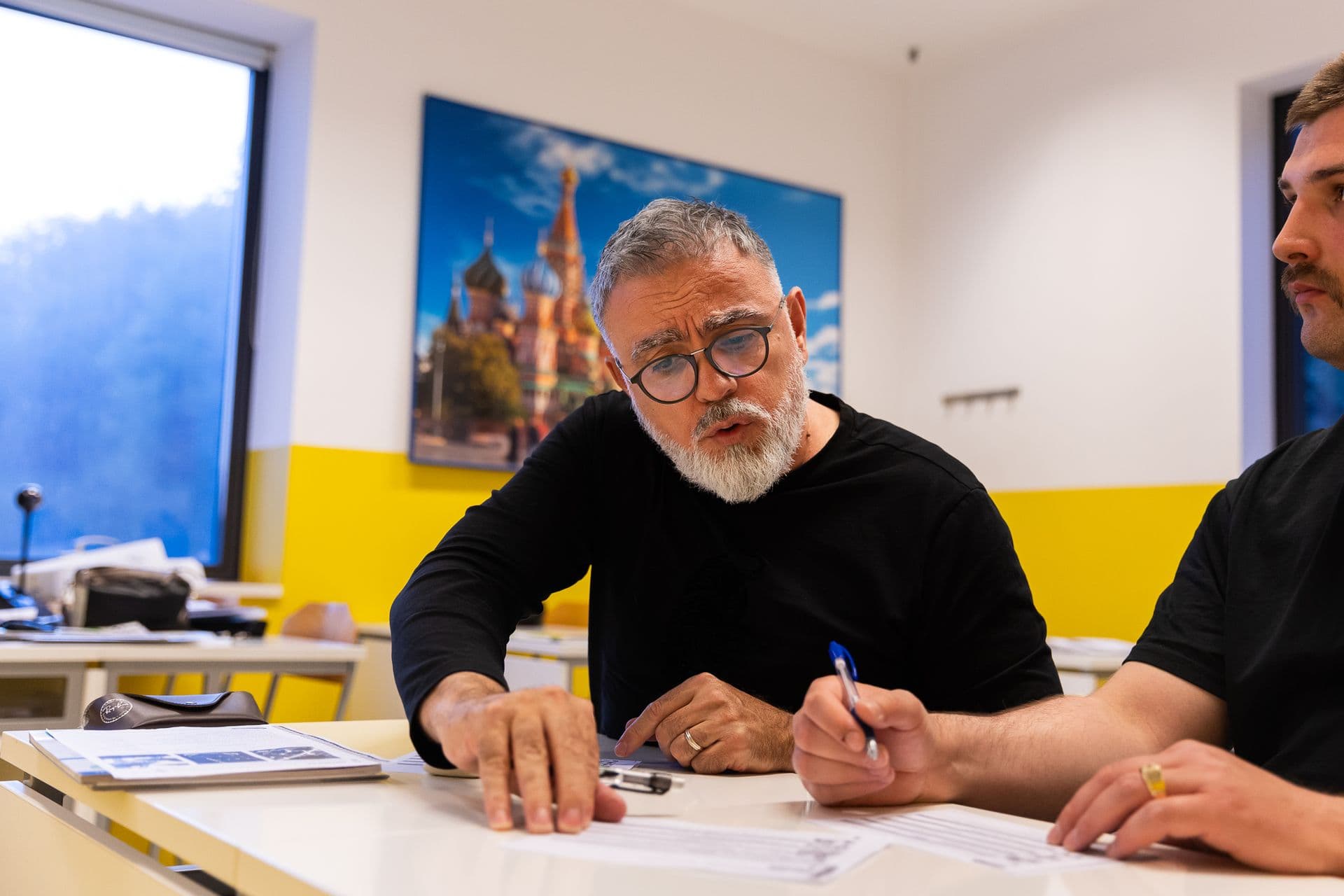 A learner in glasses writing at a desk