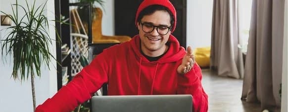 A student in a red hoodie working at a laptop