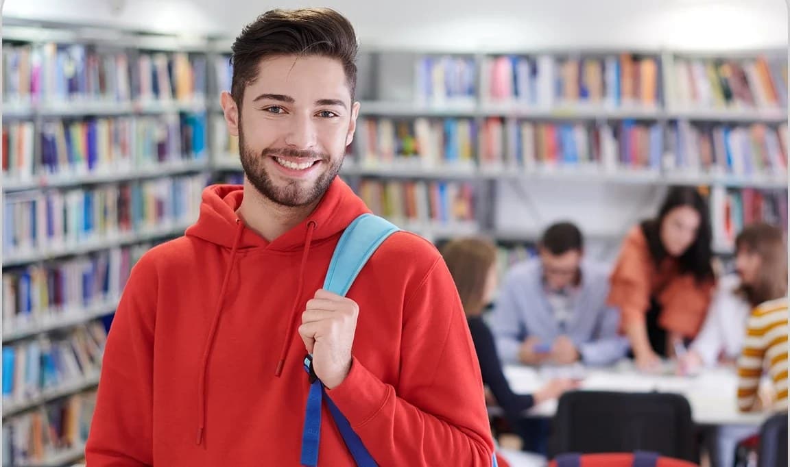 Student u crvenoj majici s ruksakom u knjižnici