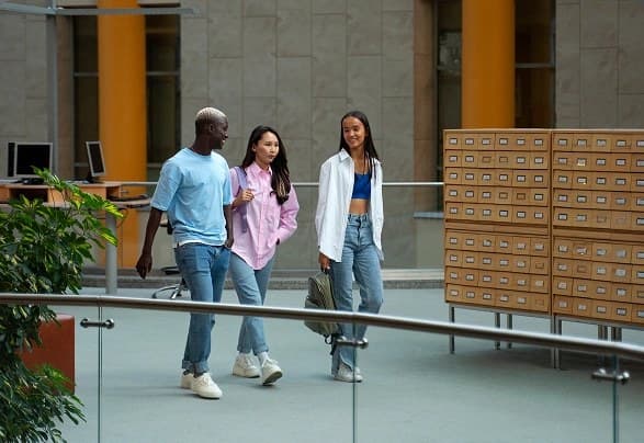 Three students walk along a university corridor